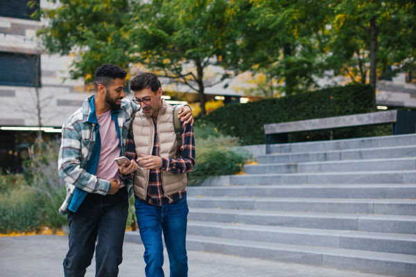 Best friends looking at smartphone, celebrating something, man's hug. Concept of male friendship, bromance.