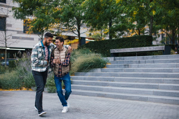 Best friends looking at smartphone, celebrating something, man's hug. Concept of male friendship, bromance.