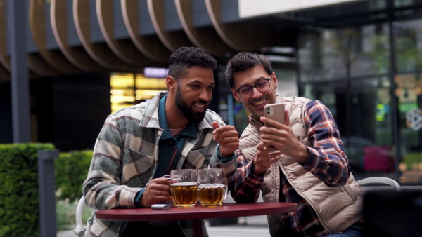 Best friends togehter, drinking beer in bar in the city and talking, having fun and laugh. Concept of male friendship, bromance.