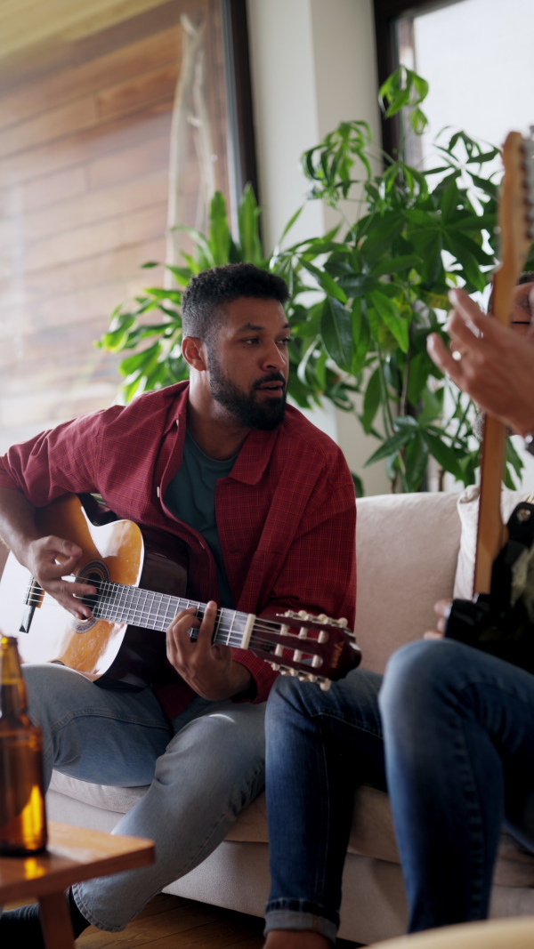 Best friends, musician jamming together. Playing music on acoustic and electric guitar together, having beer and fun. Concept of male friendship, bromance.