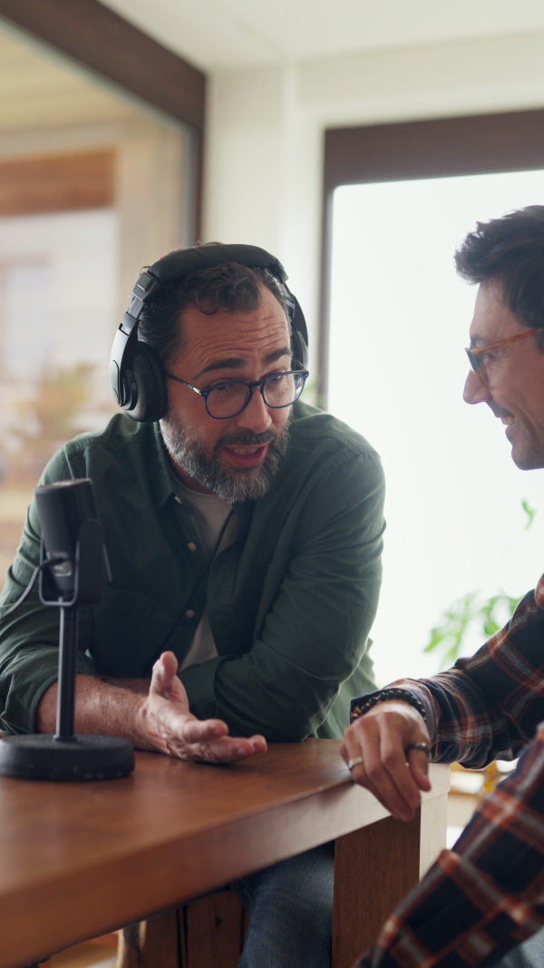 Male friends doing video podcast, talking about difficult topics, sharing sad, hurtful stories. Influencers making live video for social media, creating online content at home.