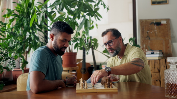 Best friends playing chess together, drinking whiskey and talking. Concept of male friendship and bromance.