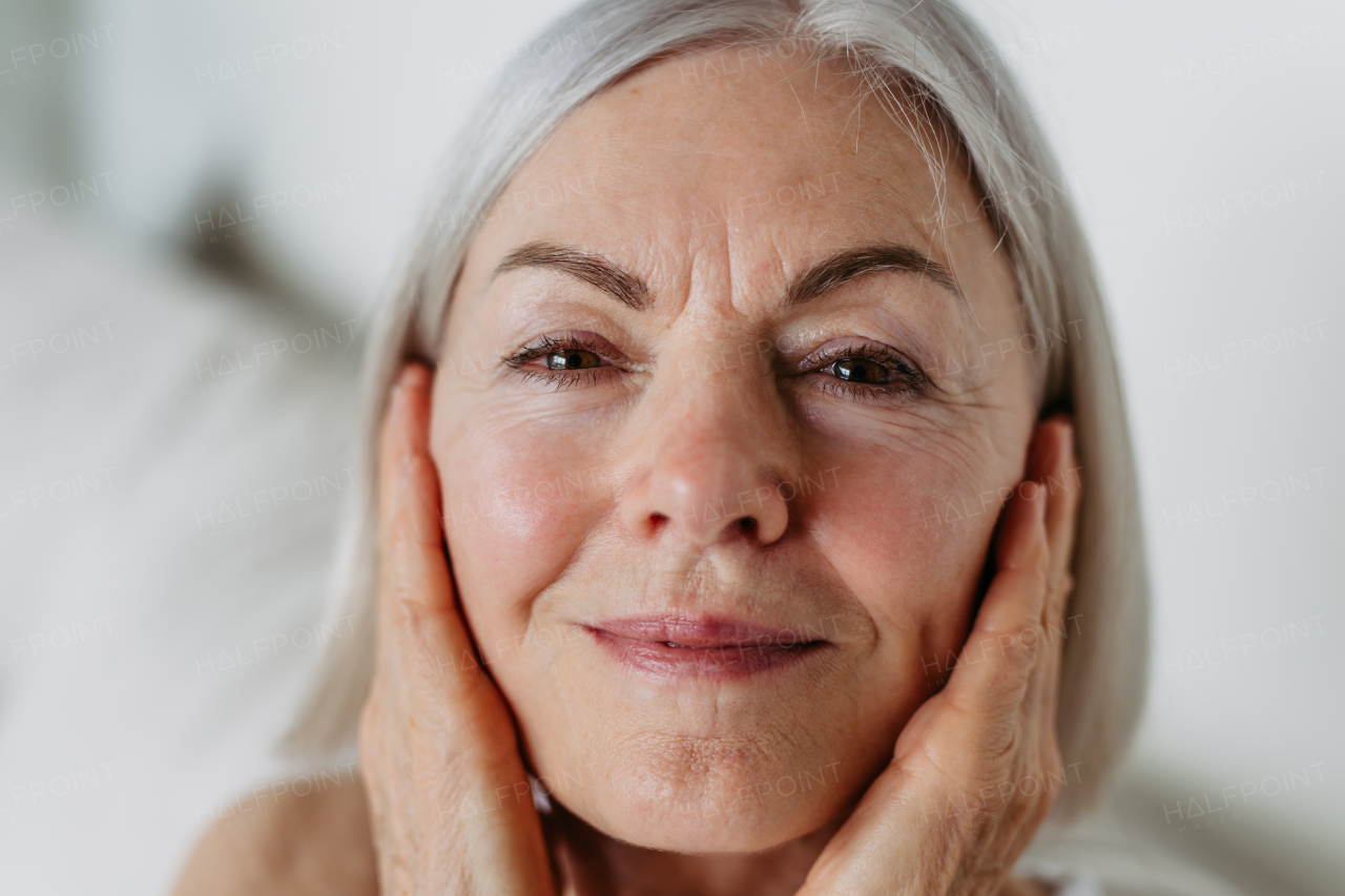 Portrait of beautiful mature woman with gray hair and soft smile, looking at camera.