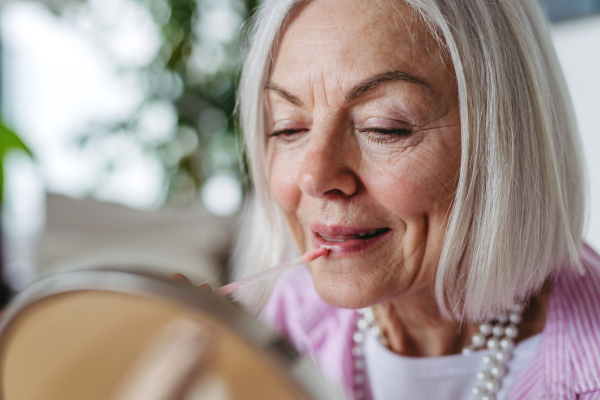 Skincare for mature woman. Portrait of beautiful older woman with gray hair putting makeup on