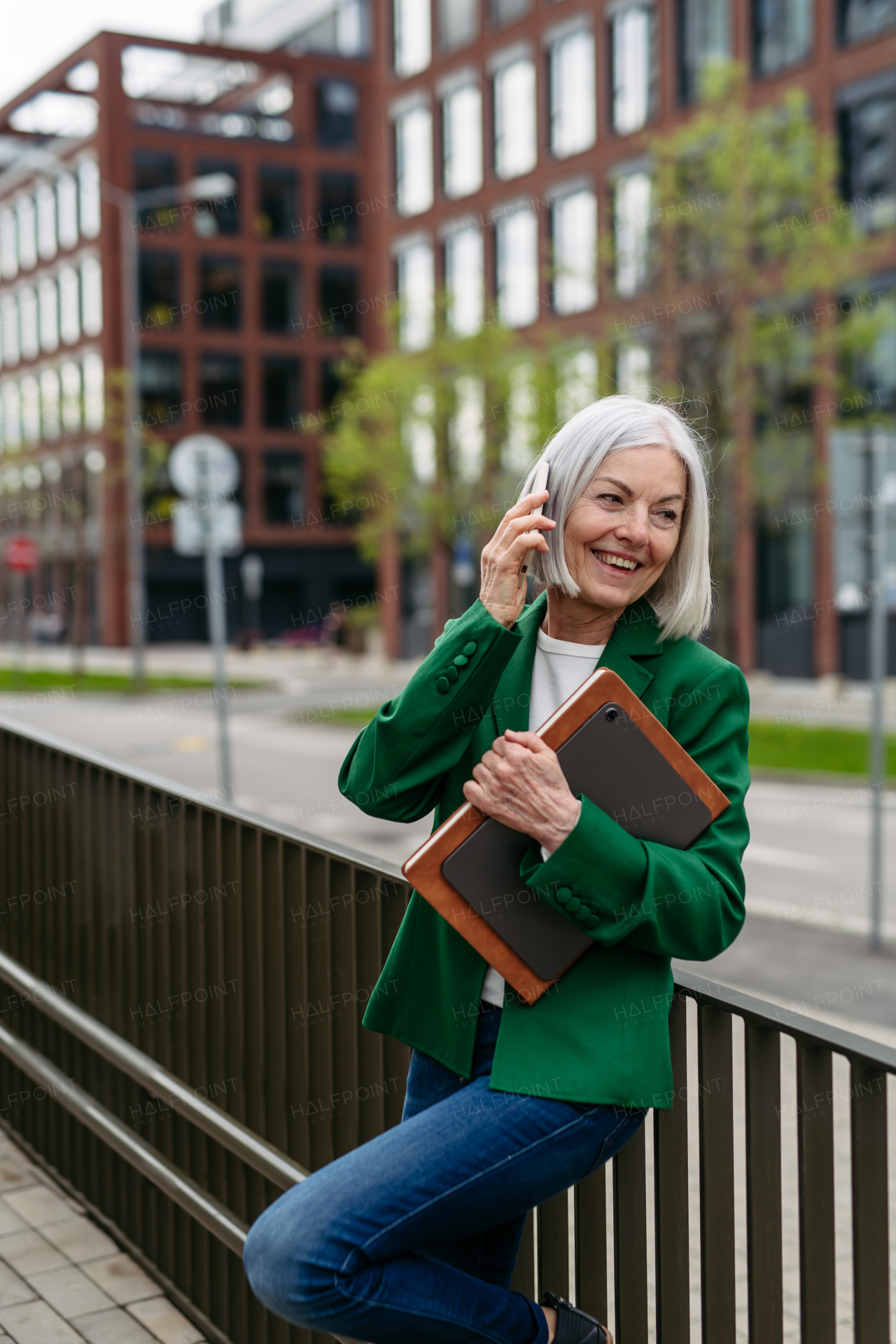 Mature businesswoman phone calling smartphone, going on business meeting in the city. Beautiful older woman with gray hair standing on city street, waiting on bus.