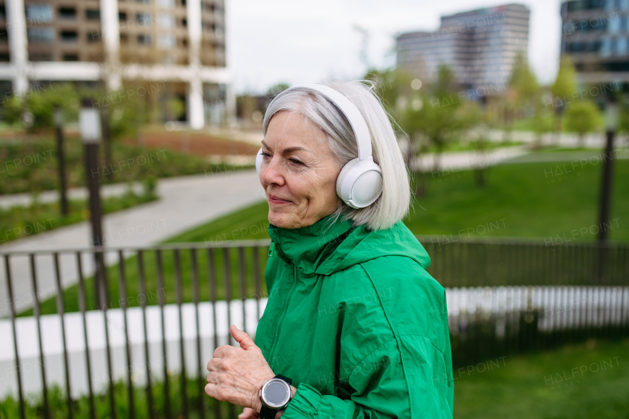 Mature woman listening music while running. Exercising after work for good mental health, physical health, and relieving stress and boost mood.