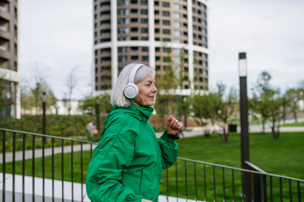 Mature woman listening music while running. Exercising after work for good mental health, physical health, and relieving stress and boost mood.