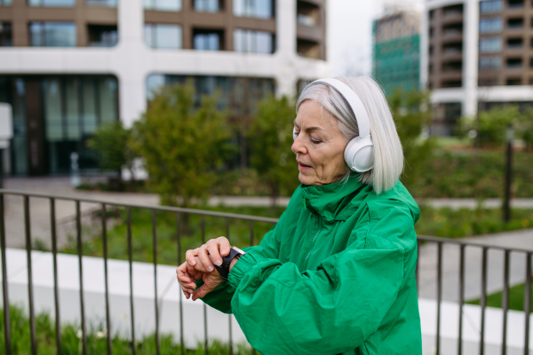 MaturMature woman checking her performance on smartwatche after run. Exercising after work for good mental health, physical health, and relieving stress and boost mood.