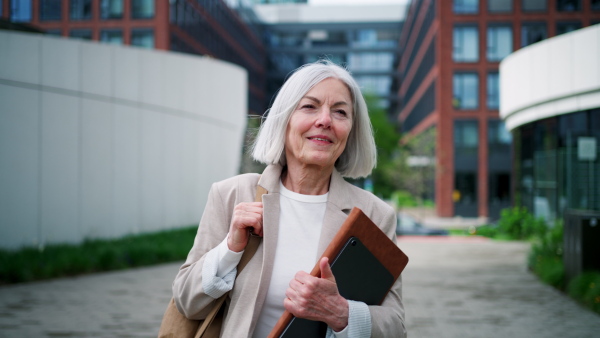 Video of stylish mature woman with gray hair on city street, going home from work.