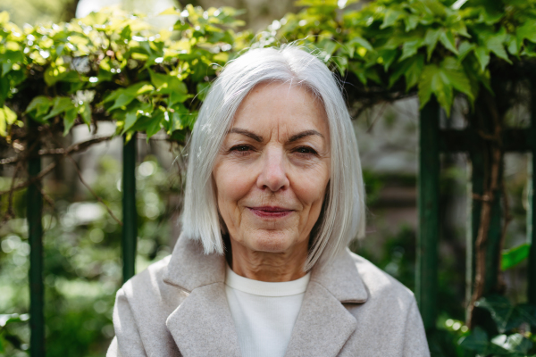 Portrait of stylish mature woman standing on city street.Beautiful older woman with gray hair outdoors.