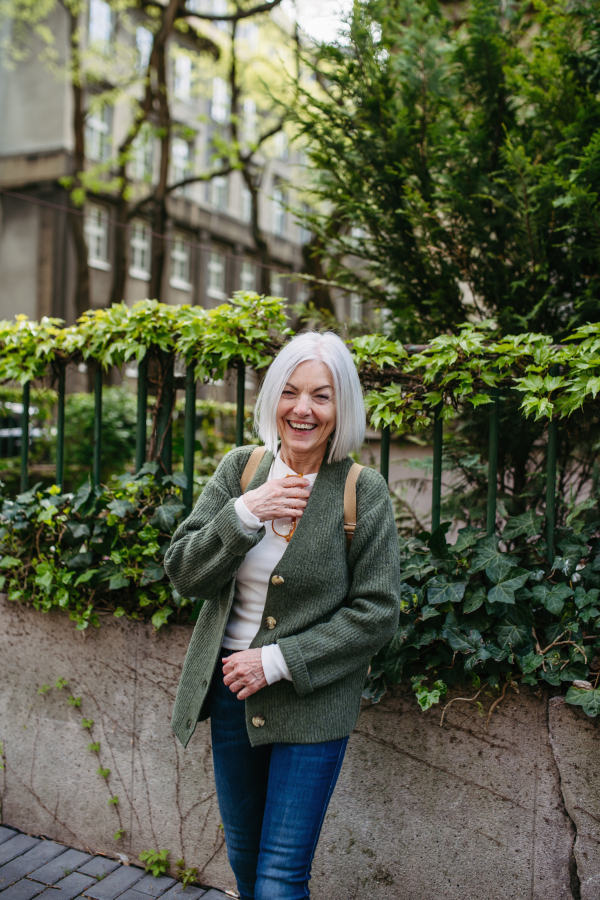 Portrait of stylish mature woman standing on city street.Beautiful older woman with gray hair outdoors.