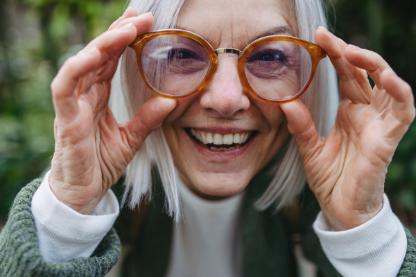 Portrait of stylish mature woman standing on city street.Beautiful older woman with gray hair outdoors.