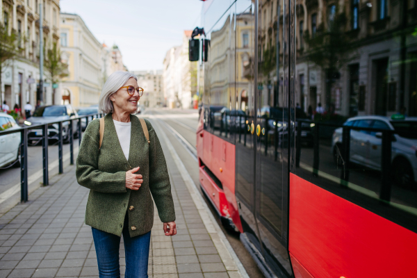 Portrait of stylish mature woman with gray hair on a city street, enjoying beautiful weater during free weekend day.