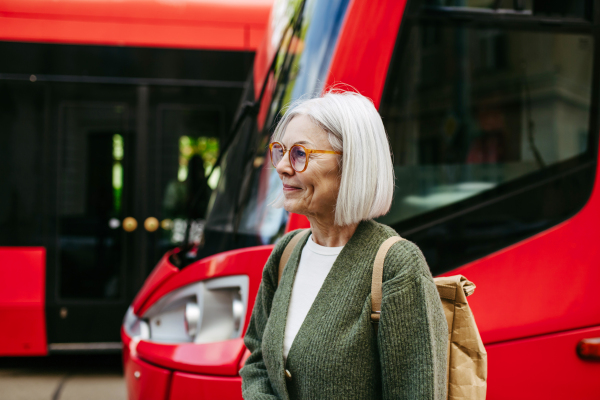 Portrait of stylish mature woman with gray hair on a city street, enjoying beautiful weater during free weekend day.