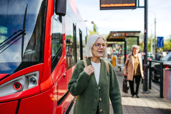 Portrait of stylish mature woman with gray hair on a city street, enjoying beautiful weater during free weekend day.