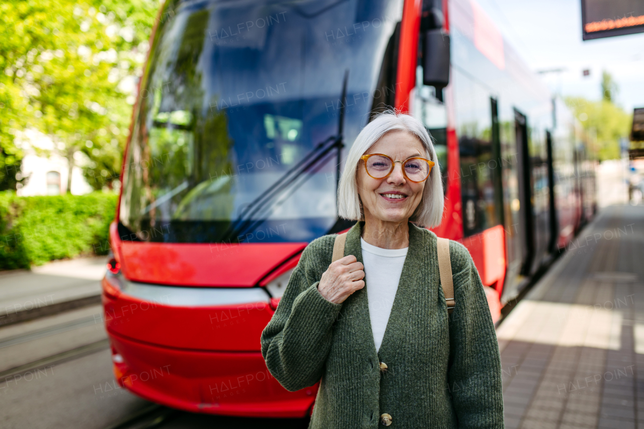 Portrait of stylish mature woman with gray hair on a city street, enjoying beautiful weater during free weekend day.