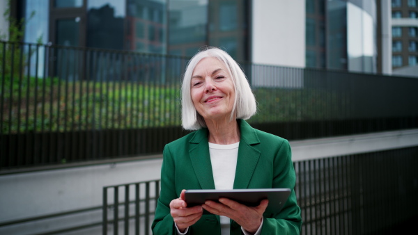 Mature woman, working on a tablet. Beautiful older woman with eyeglasses shopping online while outdoors.