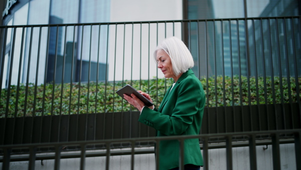 Mature woman, working on a tablet. Beautiful older woman with eyeglasses shopping online while outdoors.