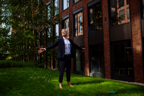 A businessman walking barefoot in park, feeling free, work life balance concept.