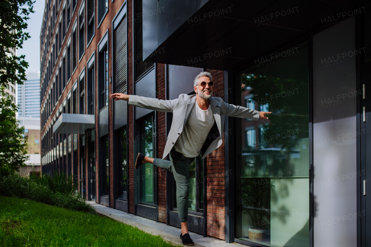 A fun portrait of happy energetic mature businessman with arms outstretched balancing on wall , feeling free, work life balance concept.