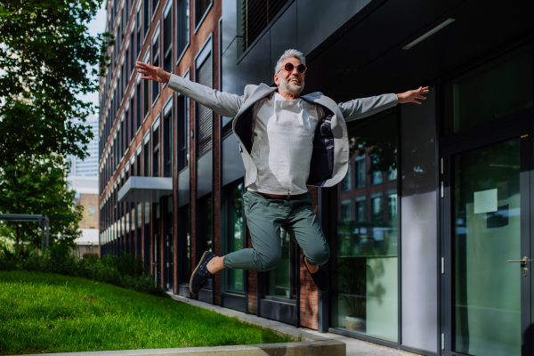 A fun portrait of happy energetic mature businessman with arms outstretched balancing on wall , feeling free, work life balance concept.