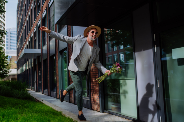 A portrait of happy energetic mature man with flower bouquet balancing on wall , feeling free, life balance concept.