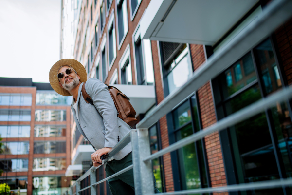 A man wearing straw hat and backpack walking in street, businessman in casual clothes in summer on the way to work.