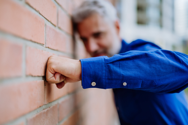 Close up of mature man fist trying to break through the wall. Concept of burn out syndrome.