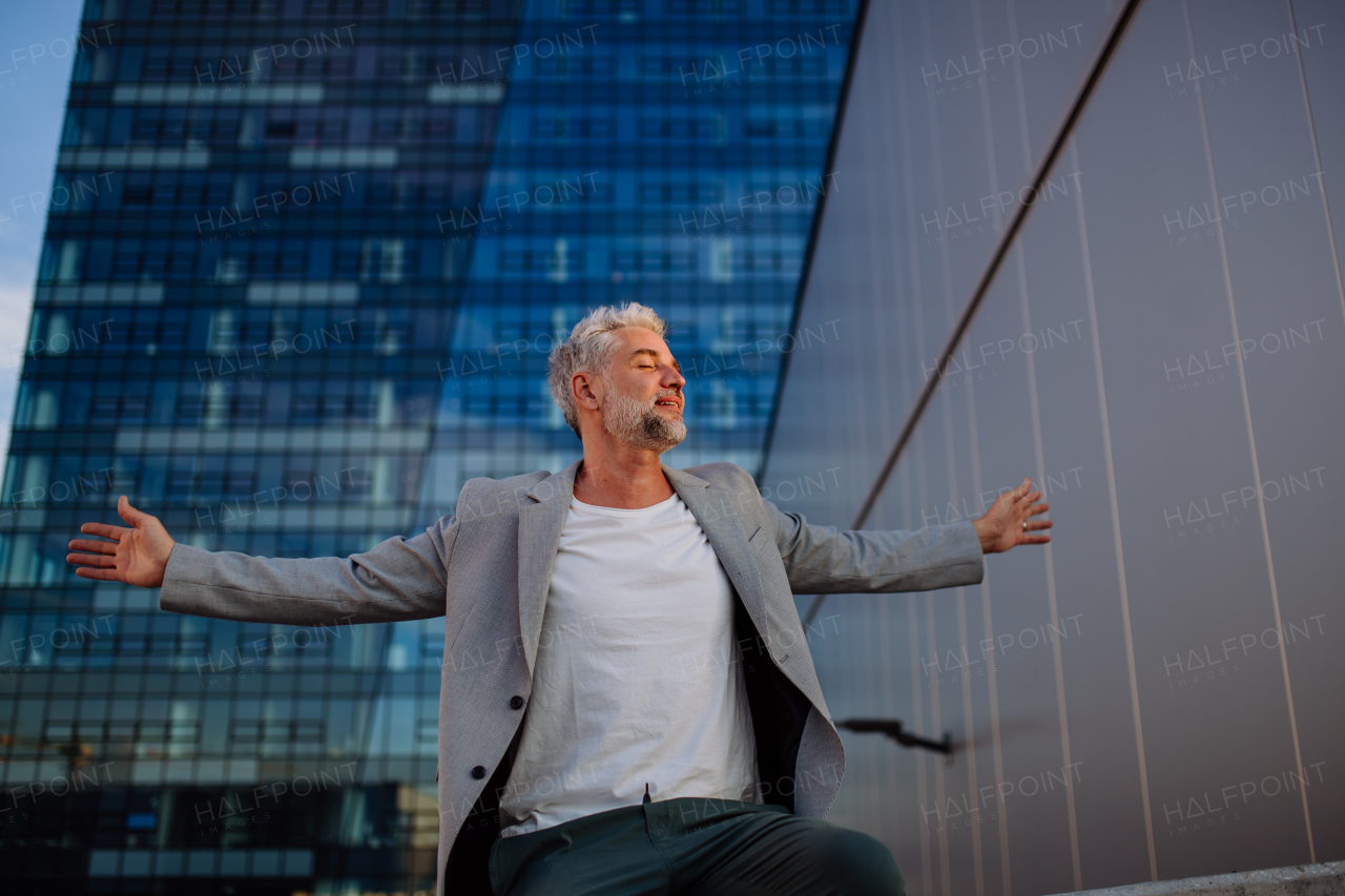 A portrait of happy energetic mature businessman with arms outstretched balancing on wall , feeling free, work life balance concept.