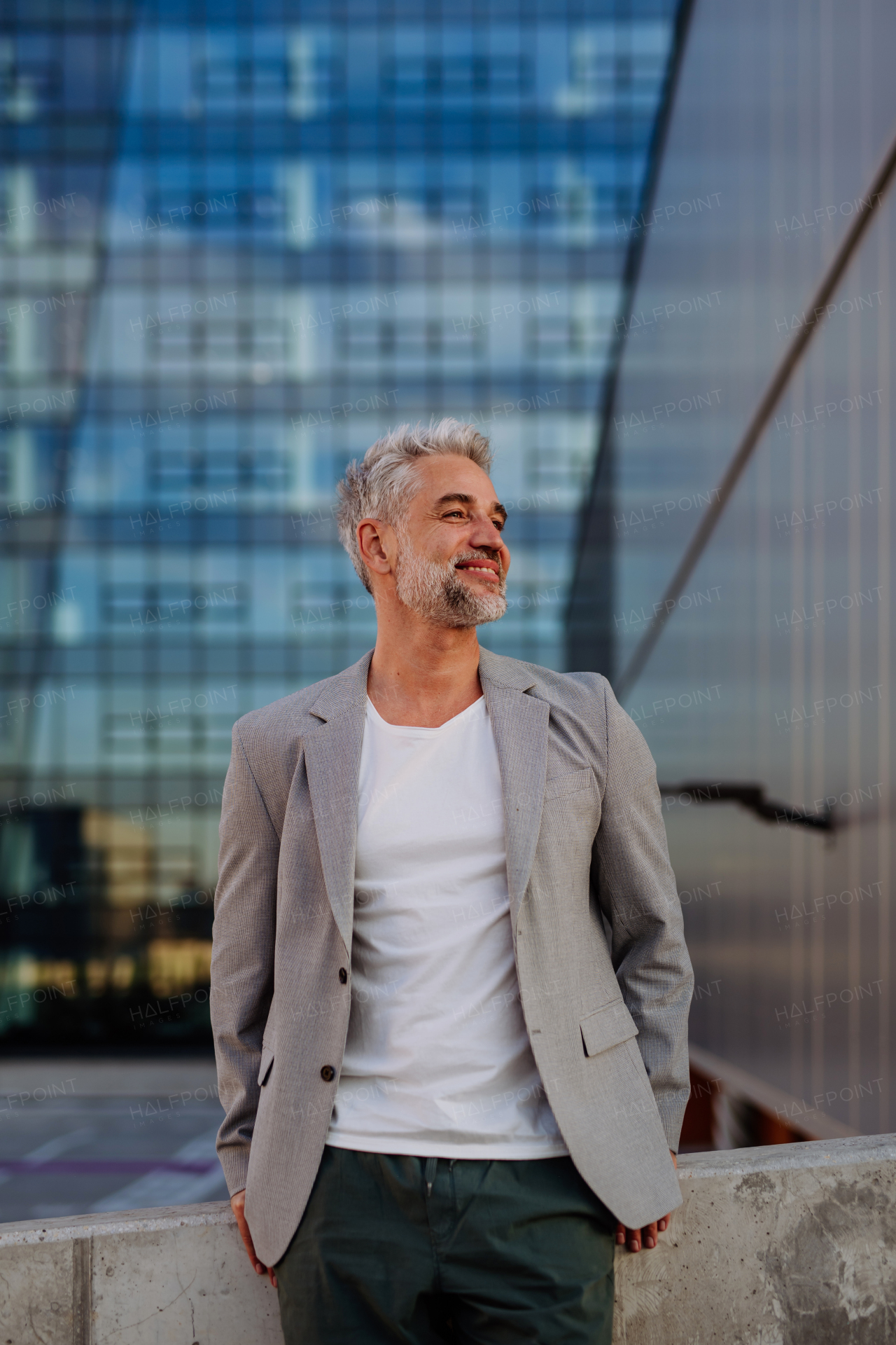 A portrait of happy energetic mature businessman in city, work life balance concept.