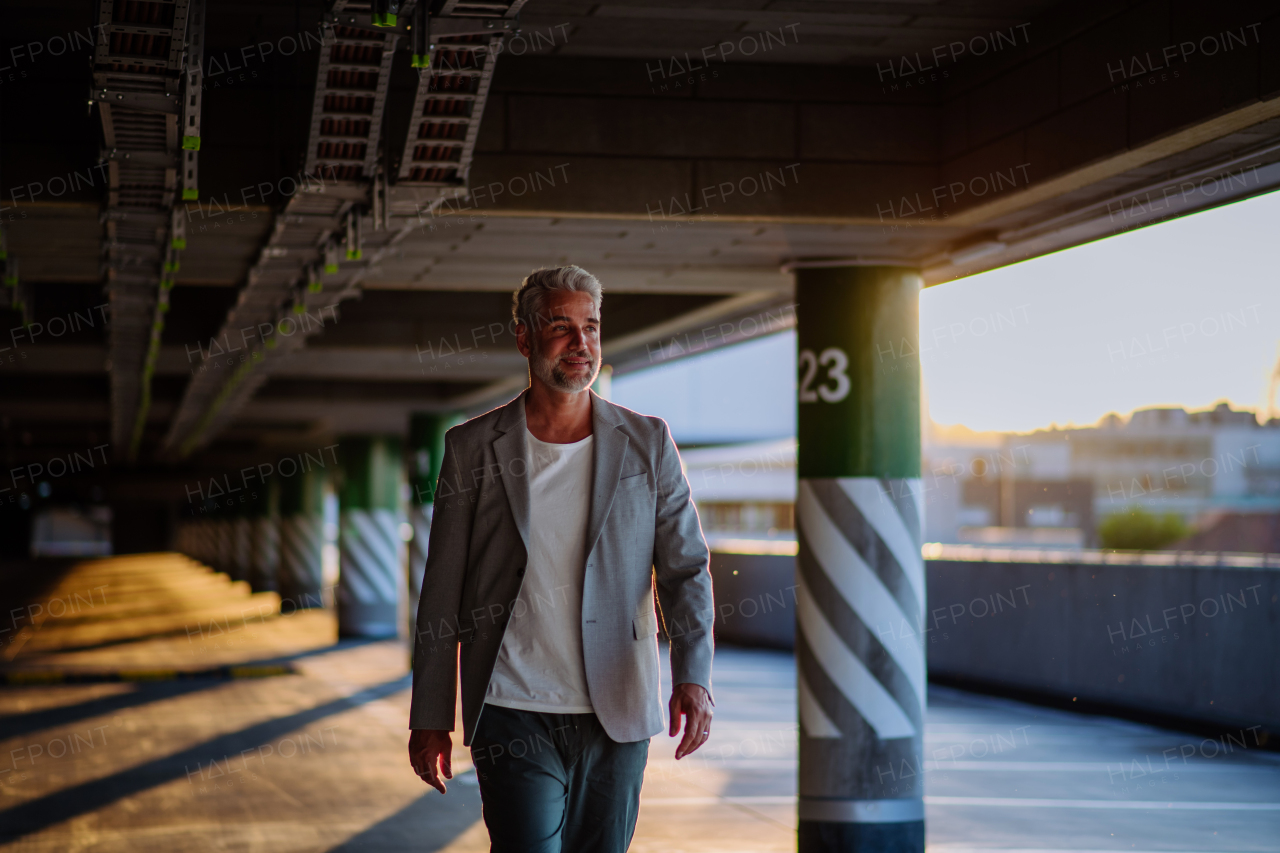 A successful happy businessman waiting in city garage, copy space, commuting concept.