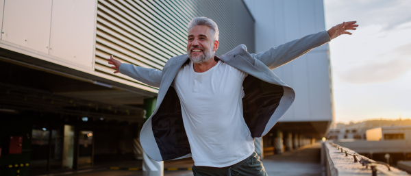 A portrait of happy energetic mature businessman with arms outstretched balancing on wall , feeling free, work life balance concept.