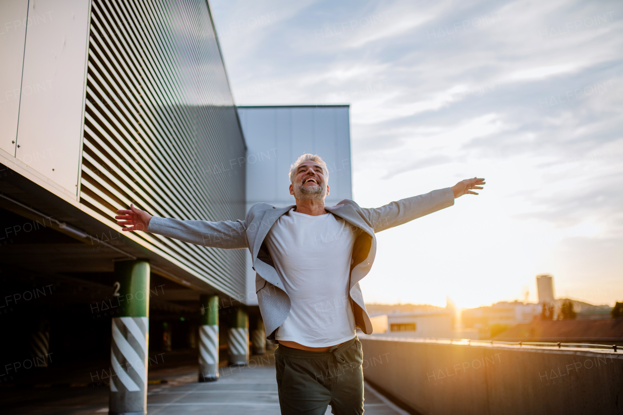 A portrait of happy energetic mature businessman with arms outstretched balancing on wall , feeling free, work life balance concept.