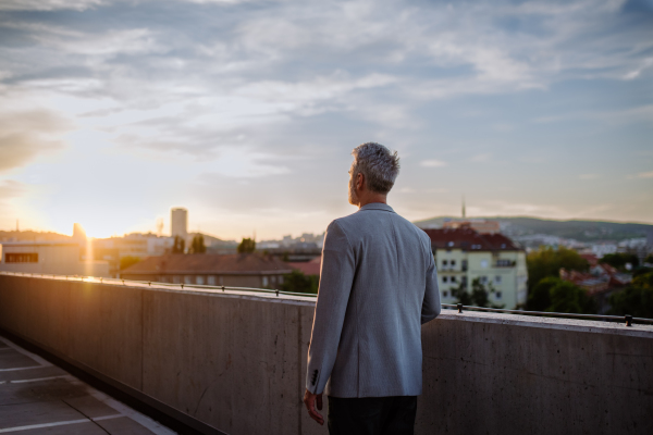 A rear view of mature businessman walking in city in evening, work life balance concept.