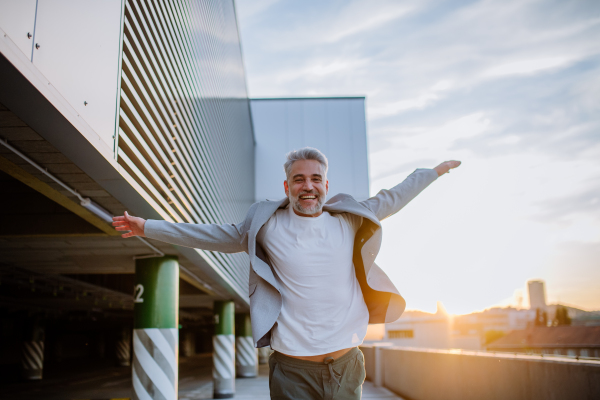 A portrait of happy energetic mature businessman with arms outstretched balancing on wall , feeling free, work life balance concept.