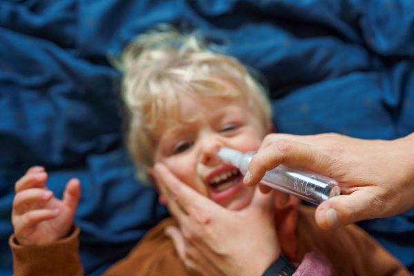 Close-up of parent holding his kid and using snot extractor.