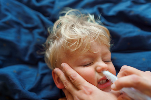 Close-up of parent holding his kid and using snot extractor.