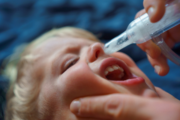 Close-up of parent holding his kid and using snot extractor.