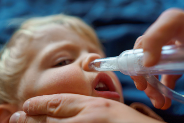 Close-up of parent holding his kid and using snot extractor.