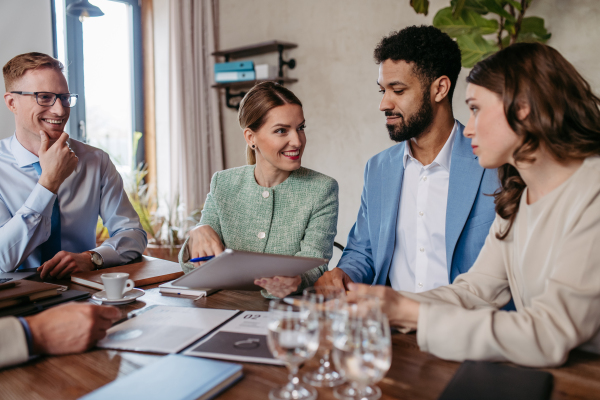 Young colleagues having casual discussion during meeting in office. Group of men and women sitting in conference room.