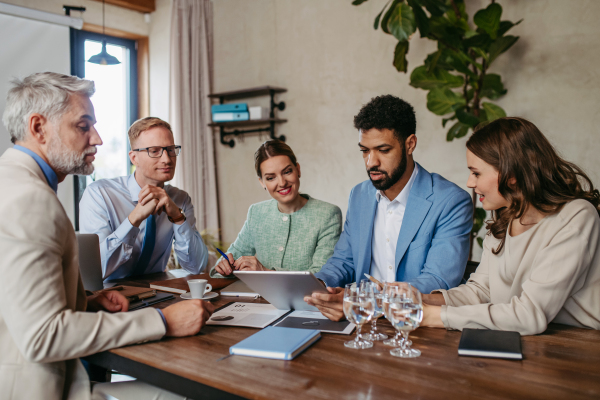 Young colleagues having casual discussion during meeting in office. Group of men and women sitting in conference room. Company workshop.