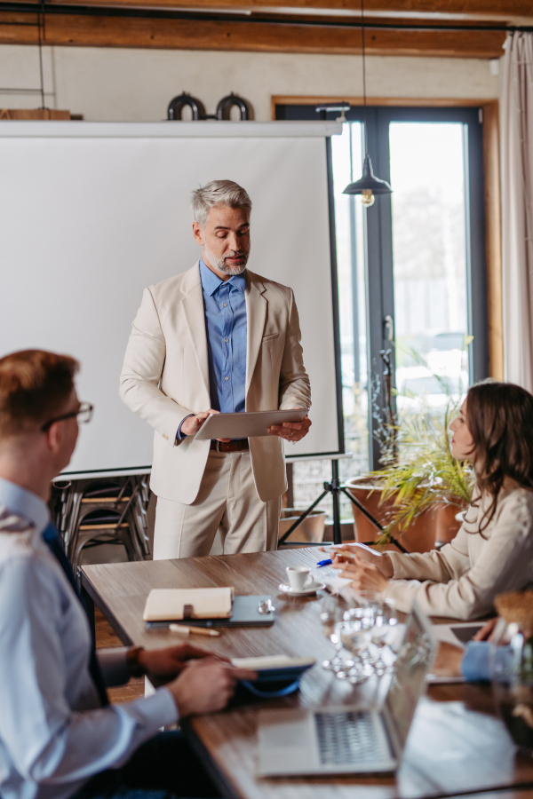 Businessman giving a presentation in a business meeting. Young colleagues and manager having casual discussion during meeting, workshop in office.