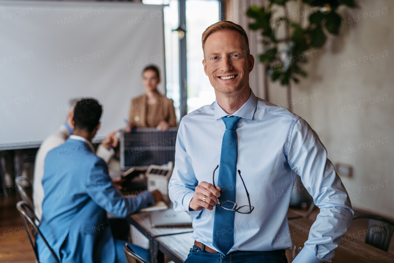 Portrait of confident young businessman during team meeting. Young colleagues discussing photovoltaic panels, clean, green, energy. Business using renewable energy.