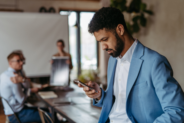 Portrait of confident young businessman using smart phone during meeting.Young colleagues discussing photovoltaic panels, clean, green, energy. Business using renewable energy.