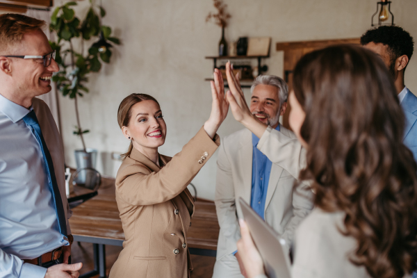 Happy successful multiracial business team giving a high fives gesture as they laugh and cheer their success