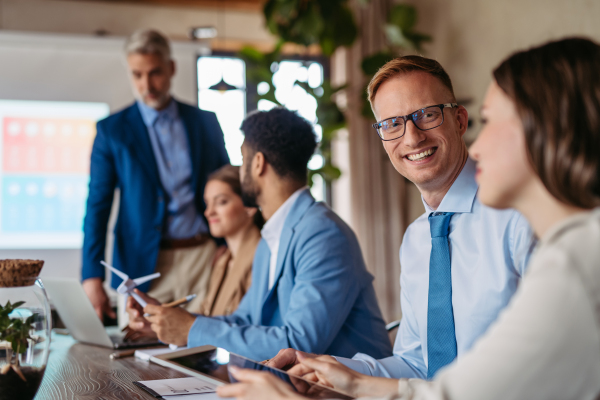 Corporate business team and manager in meeting, discussing renewable energy options for business. Group of men and women sitting in conference room.