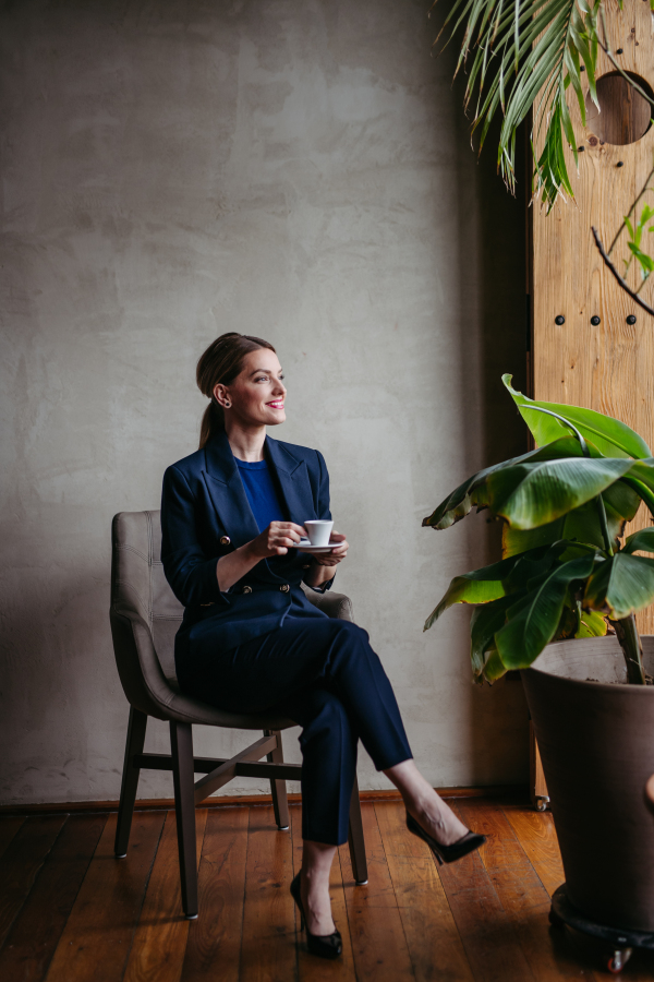 Portrait of a young woman sitting near window in green office full of plants.