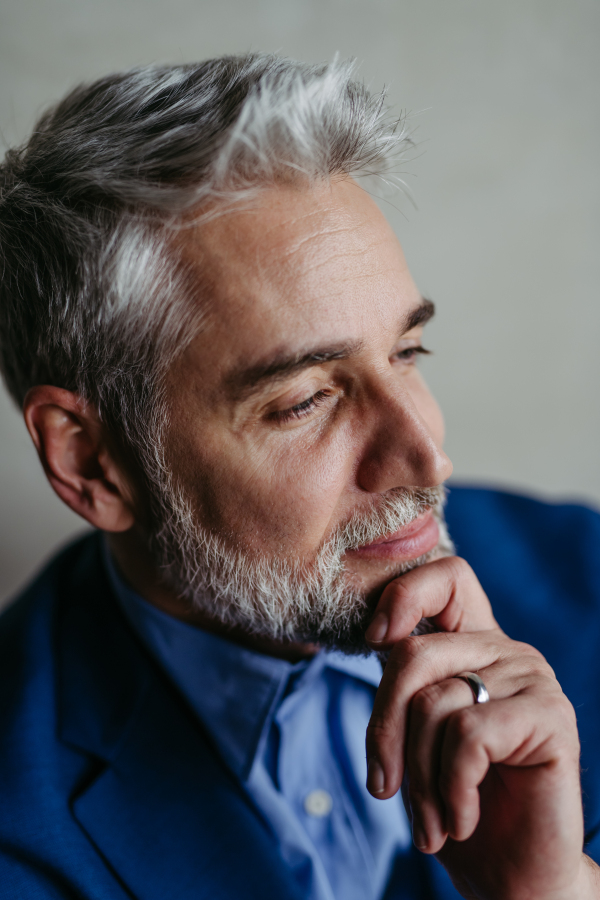 Handsome man with gray hair and beard smiling, looking aside studio portrait. Close-up portrait of a charismatic businessman, manager, ceo, lawyer.