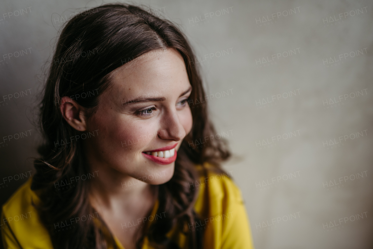 Young woman smiling looking aside studio portrait on gray copy space. Close-up portrait of a charismatic businesswoman, manager, ceo, lawyer.