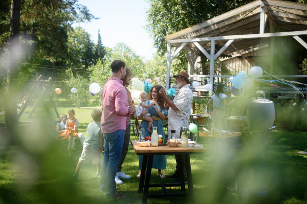 Friends and family talking and having fun at a summer bbq summer garden party, preparing food at grill.